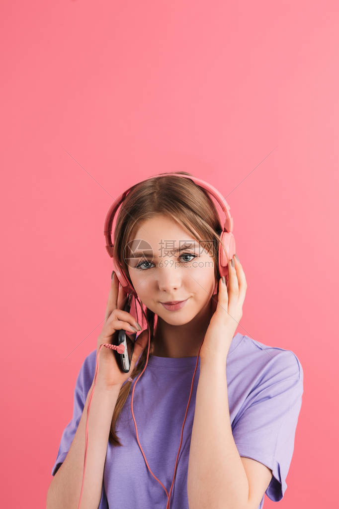 带着两条辫子身穿淡紫色T恤戴着耳机听音乐面带微笑的年轻女孩图片