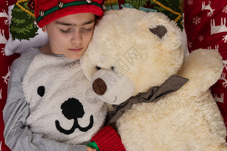 圣诞时在家睡觉的姑娘和大熊泰迪在一起图片