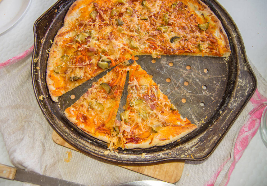 新鲜烤的自制披萨在一个有奶酪和火腿的金属锅上图片
