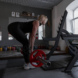 运动身体的完美年轻女子正在健身房里用巴铃做锻炼图片