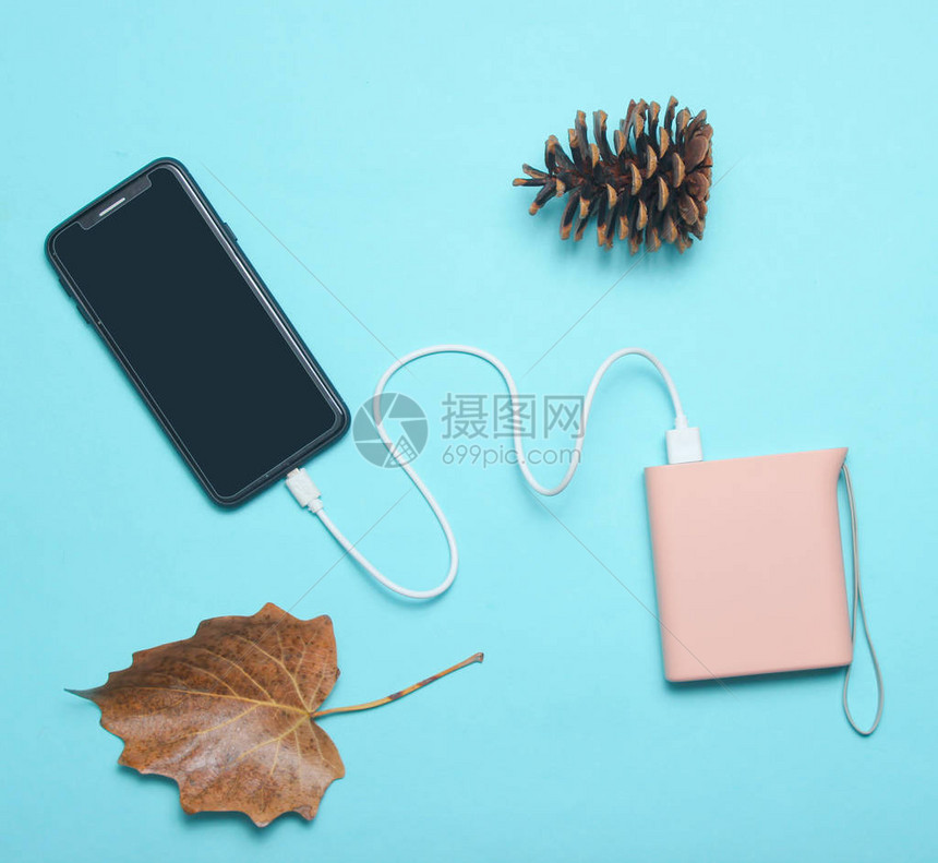 现代智能手机用电源银行针筒秋叶和蓝色背景充电顶级观图片