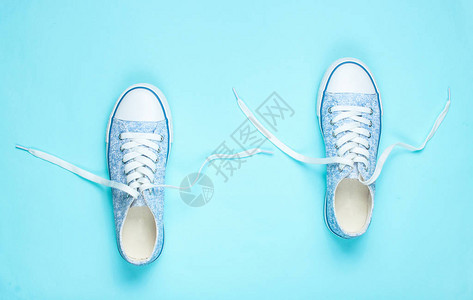 蓝色背景上带解开鞋带的时尚运动鞋图片