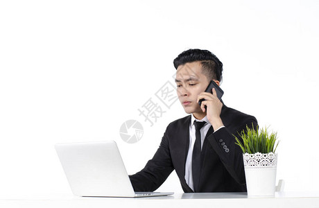 年轻商人打个电话用他的笔记本电脑工作图片