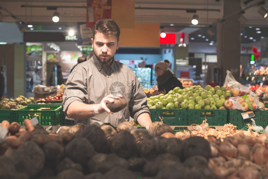 戴着手套的男人在超市里挑选蔬菜图片