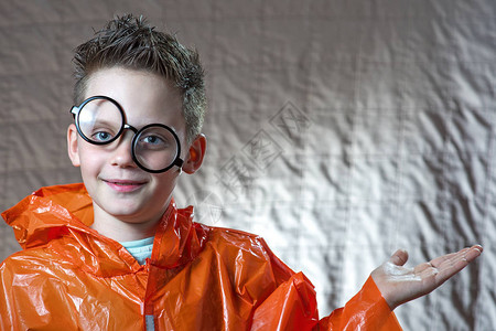 一个穿着明亮橙色雨衣和圆眼镜的男孩图片