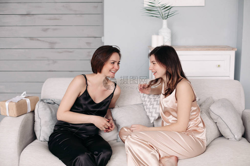 两个年轻姐妹在家坐在沙发上聊天的侧视图图片