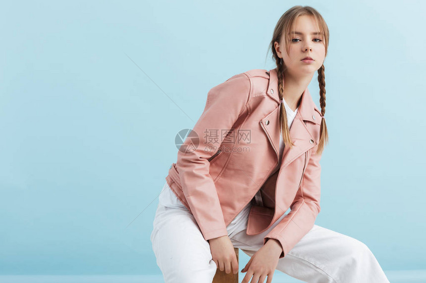 穿着粉红皮夹克和白色牛仔裤的两条短胸衫的年轻有吸引力的女孩图片