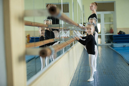芭蕾机旁的小女孩课程编排年轻的芭蕾舞演员体操初始组的图片