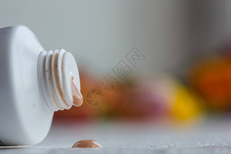 白桌上有奶油和露面盖子的塑料嘴管用于身体护理的化妆品在模糊图片
