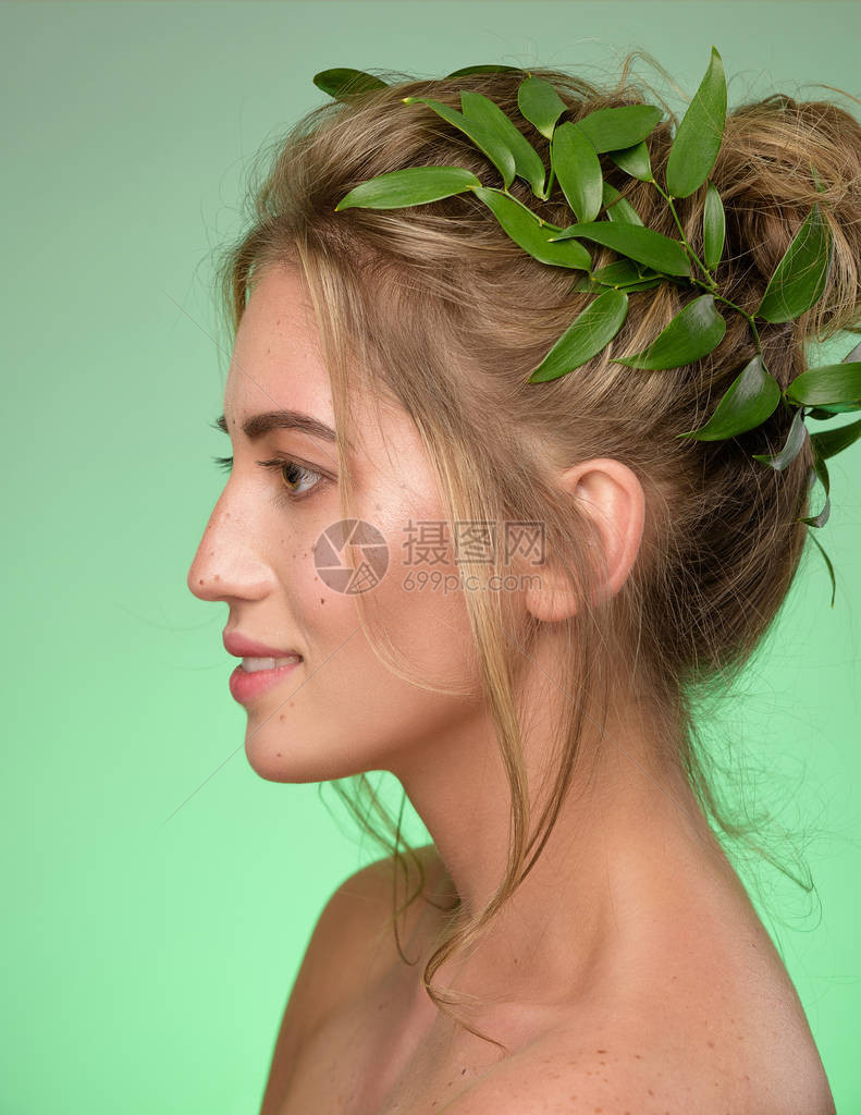有雀斑的女人脸上的美丽肖像戴着一顶绿叶冠美丽的金发女spa模型与完美清新干净的皮肤看着相机和微笑青年和护肤理念绿色背景图片