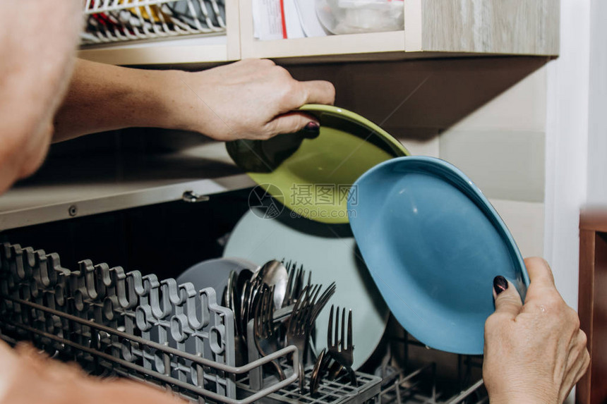 女手把盘子放在一个敞开的洗碗机里图片