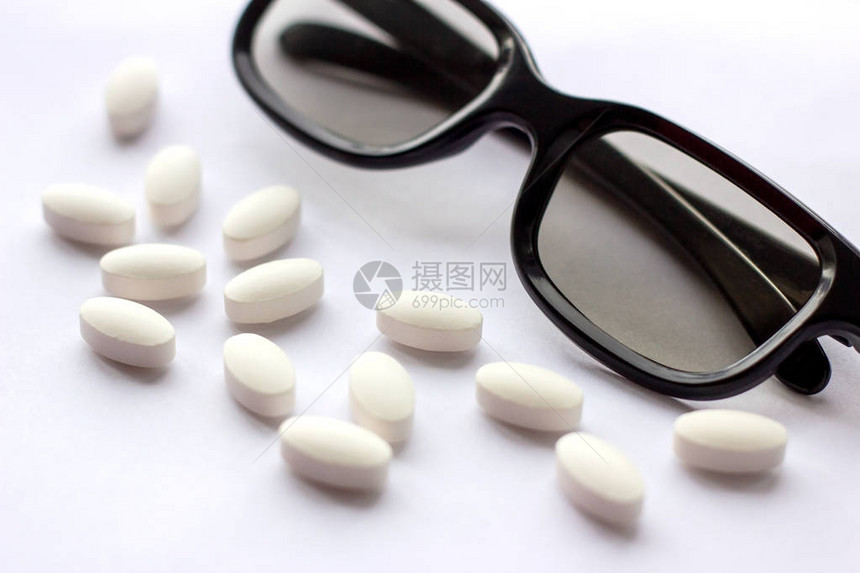 浅色背景上带眼镜的白色药丸和平板电脑药学和医学概念专注于眼科疾病的制药行业选图片