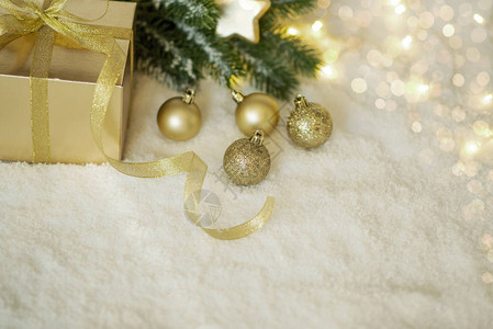 带有冷杉树枝装饰和礼品盒的散焦灯的金色圣诞背景选择对焦带有文本复制空图片