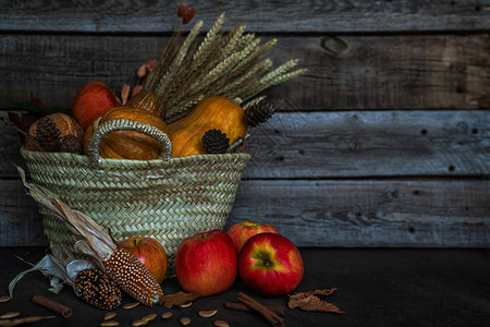 老式板上的彩色秋季蔬菜在柳条筐的秋天装饰品一个有南瓜葫芦南瓜视锥细胞小麦和树叶的聚宝盆带有复制空间的色调图背景图片