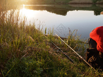 拿着钓鱼竿的渔夫坐在湖边图片