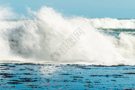 海浪拍打着海岸附近的石头白色泡沫从海浪中涌出蓝天海图片