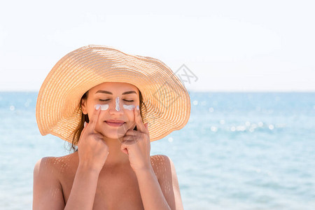 戴帽子的美丽的年轻女子正像印度人一样在眼睛和鼻子上晒太阳保护太阳的概图片