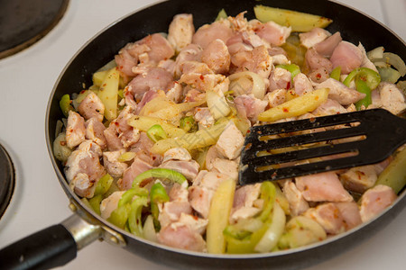 鸡肉在电炉上的煎锅中炸家常菜图片