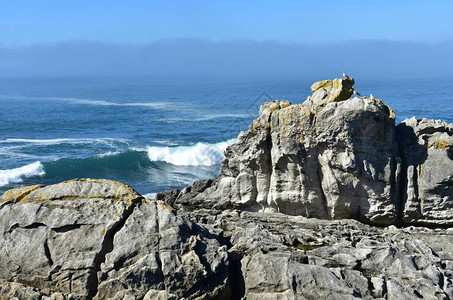 与波浪破碎雾和蓝天空的悬崖西图片