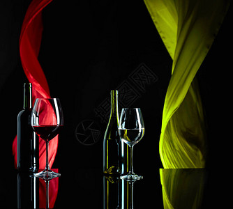 黑色反射背景的红酒和白葡萄酒日落幕在风中挥舞背景图片