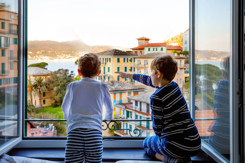 两个小男孩从意大利古里亚地区的窗户欣赏风景五渔村和波托菲诺令人敬畏的村庄在美丽的意大利城市度假图片