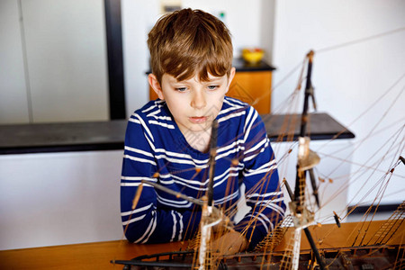 金发小男孩在室内玩帆船模型放学后在家玩游艇的兴奋的孩子快乐的男孩建图片