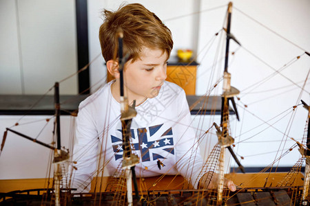 金发小男孩在室内玩帆船模型放学后在家玩游艇的兴奋的孩子快乐的男孩建图片