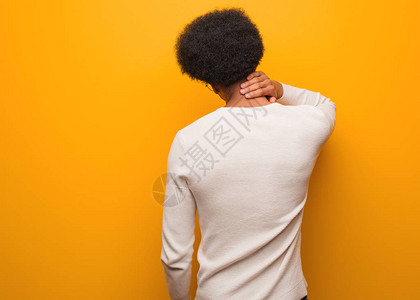 背着橙色的墙从背后思考某件事的年轻非洲男人图片