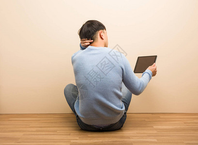 年轻的人坐着在用平板上从图片