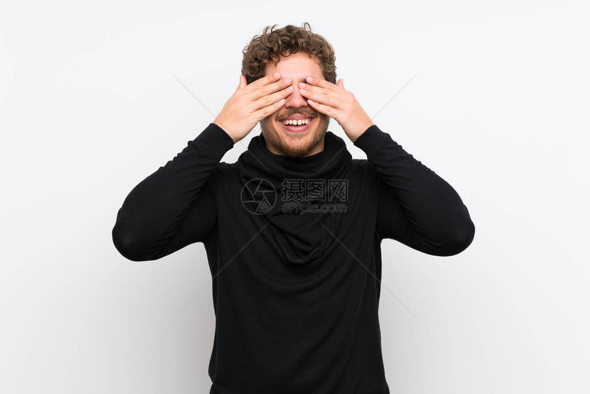 金发男子在孤立的白墙上用手遮住眼睛图片