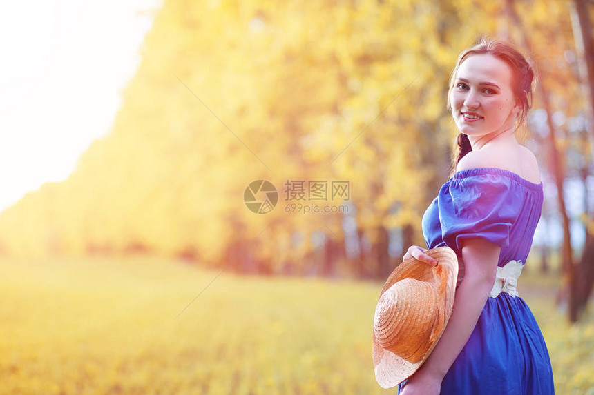 年轻漂亮的女孩穿着自然一个戴帽子的女孩在公园里散步带着篮子在城外野图片