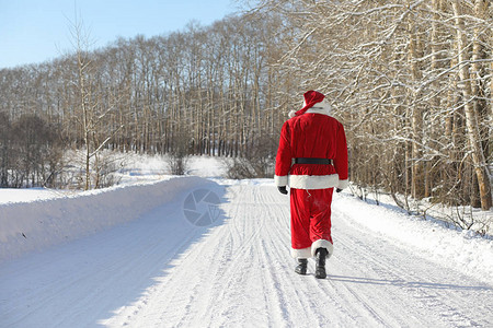 走还是留圣诞老人带着外面的礼物来了穿着红色西装留着胡子戴着眼镜的圣诞老人正沿着通往圣诞节的路走圣诞老人给孩背景