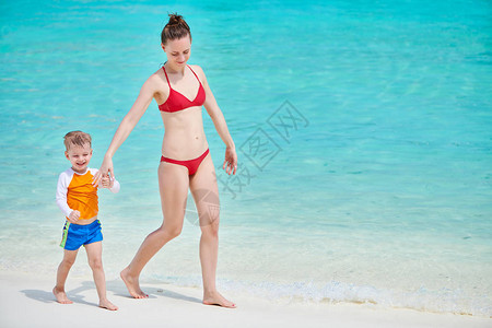 三岁的幼儿男孩和母亲一起在海滩上散步图片