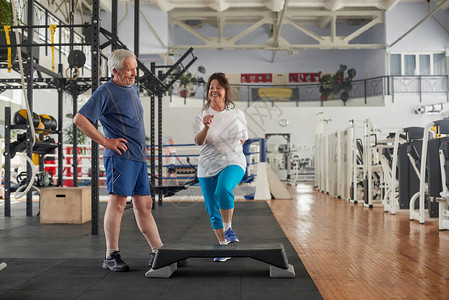 快乐的老妇人在健身俱乐部训练她的腿图片