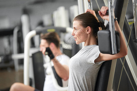 在健身房健身锻炼年轻坚定的健身女人在现代健身房的机器上做卧推保图片