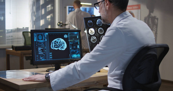 在监测和分析X射线和脑扫描时坐在监控台的背景图片