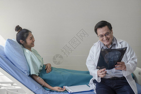 高级男医生一边讲解病人床上的X光片图片
