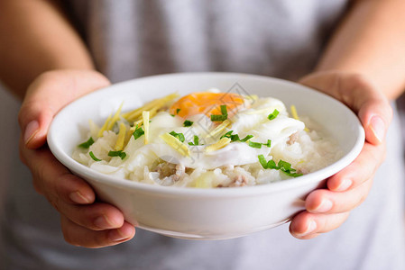 泰国大米汤或软煮米饭手握碗里图片