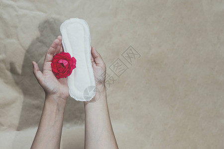 女手上拿着红玫瑰的卫生巾显示女月经周期图片