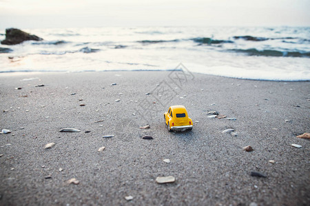 夏日阳光下沙滩上的黄色玩具车图片