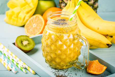 热带水果香蕉橙色芒果菠萝基维和黄色冰雪果汁的夏季特异食品概念图片