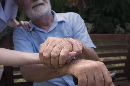 老人幸福和护士的手在疗养院的花园里图片