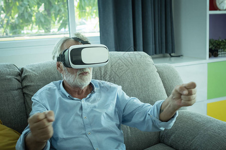 坐在沙发上和在客厅用VR耳机玩游戏以放松气氛的图片