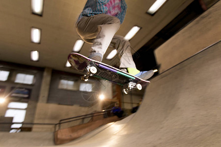 匿名青年男子玩滑冰把戏的行动镜头在滑板公园空中飞翔图片