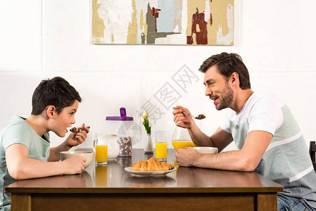 父亲和儿子在厨房吃早餐互相看着图片