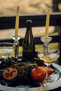 石榴葡萄酒和蜡烛放在装有首饰和棺材的盘子上图片