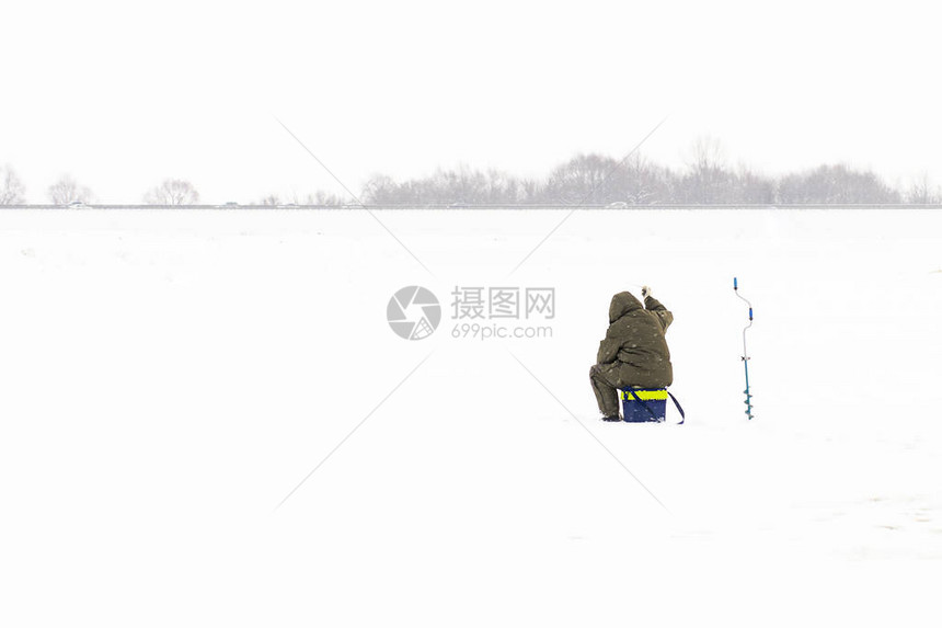 在冰上冷冻的冬季捕鱼渔民或图片