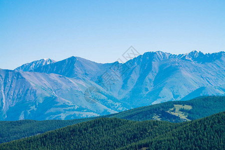 山上的巨山和冰川与森林蓝色晴朗的天空下的雪山脊高地的雪峰永久冻土图片