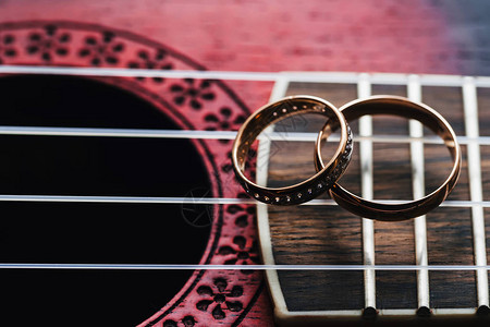 两个金婚戒躺在吉他弦上特写图片