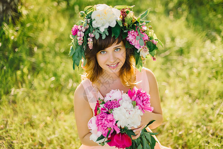 一个快乐笑的女孩的肖像带着花圈朵和一束白种图片